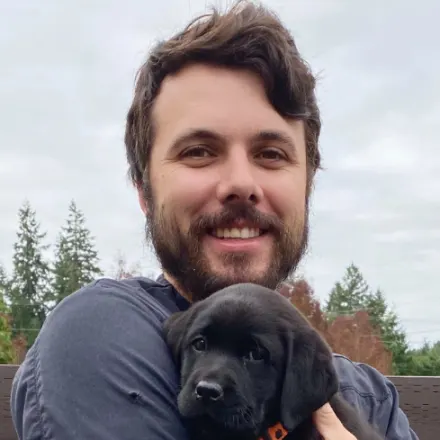 Dr. Ethan Walsh holding a little black puppy